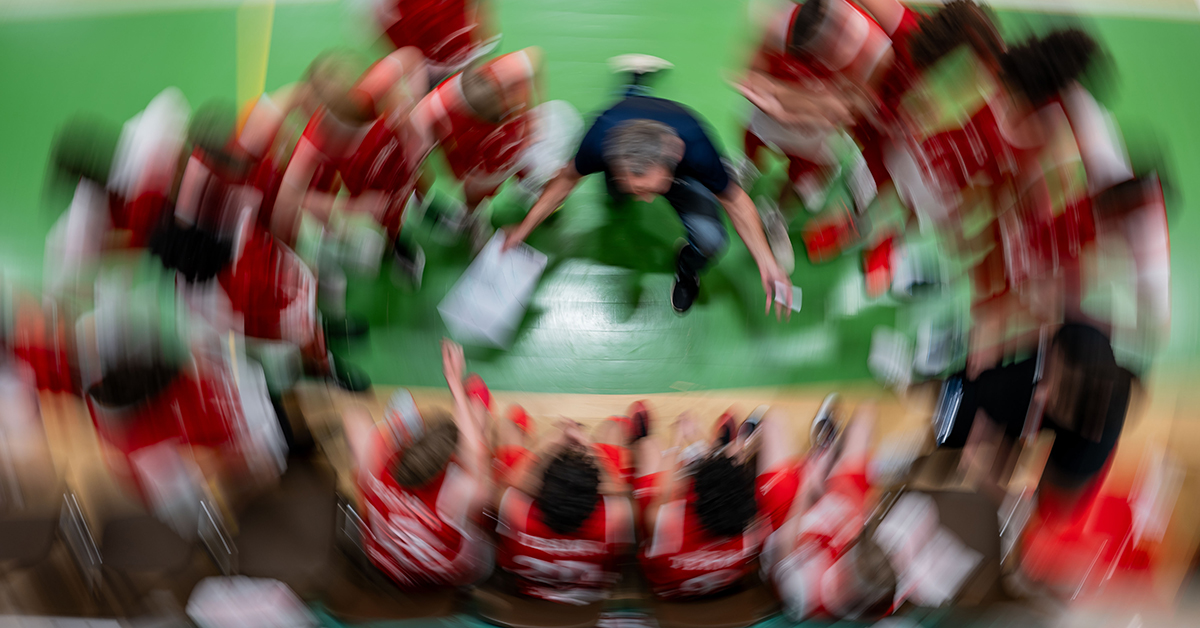 Suddig bild på en idrottsledare omgiven av aktiva