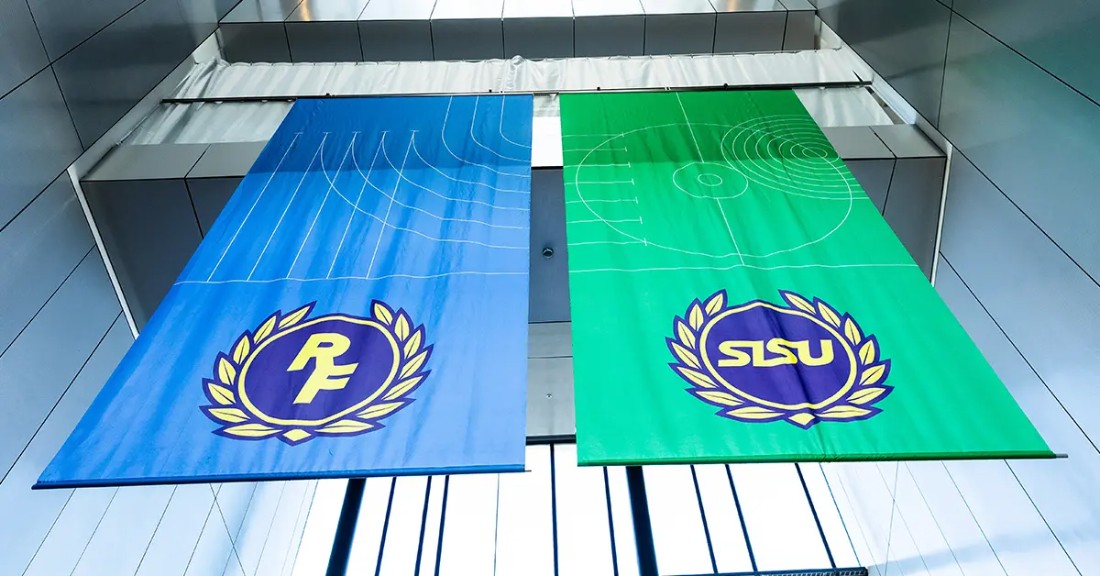 Två flaggor syns på bilden, en blå med RF logga och en grön med SISU logga 